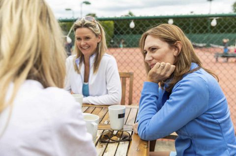 Group of women talking in a cafe at tennis club after a match